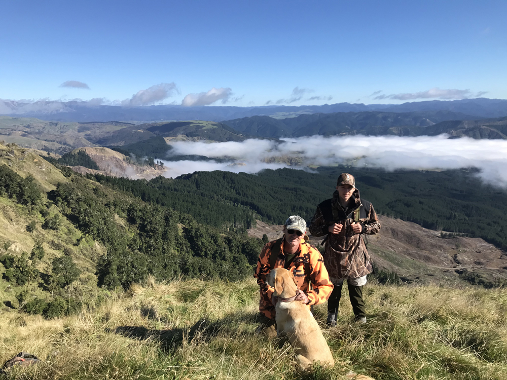 Sam and his son Max in front of a beautiful view from the top of one of Rayonier's Hawke's Bay, New Zealand, forests
