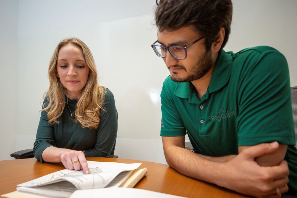 Two people review a stack of papers outlining a project plan.