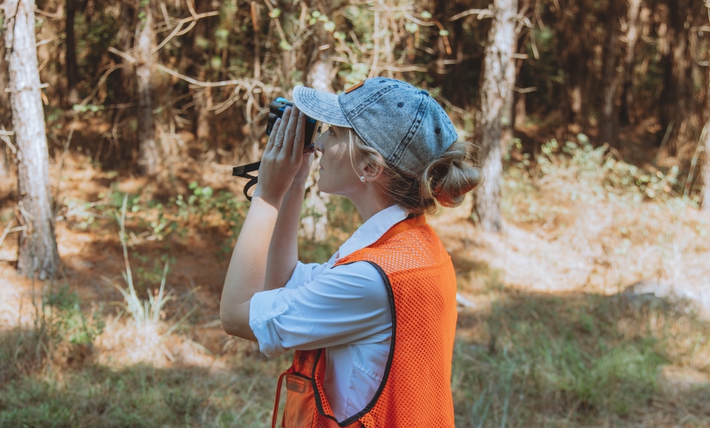 Shawn DeRome looks through a hypsometer while assessing the value of a timber stand.