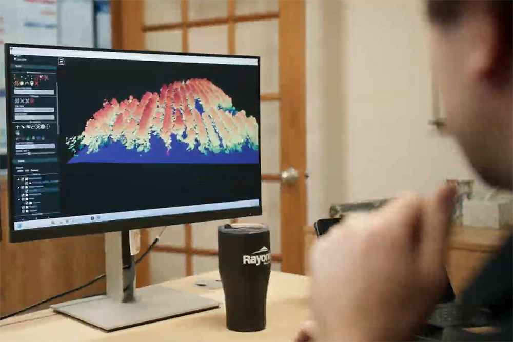 New England Forestry Remote Sensing employee views a 3D rendering of a forest on a computer.